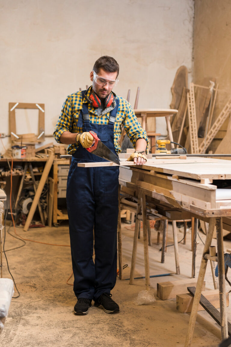 male-carpenter-cutting-wooden-plank-with-handsaw